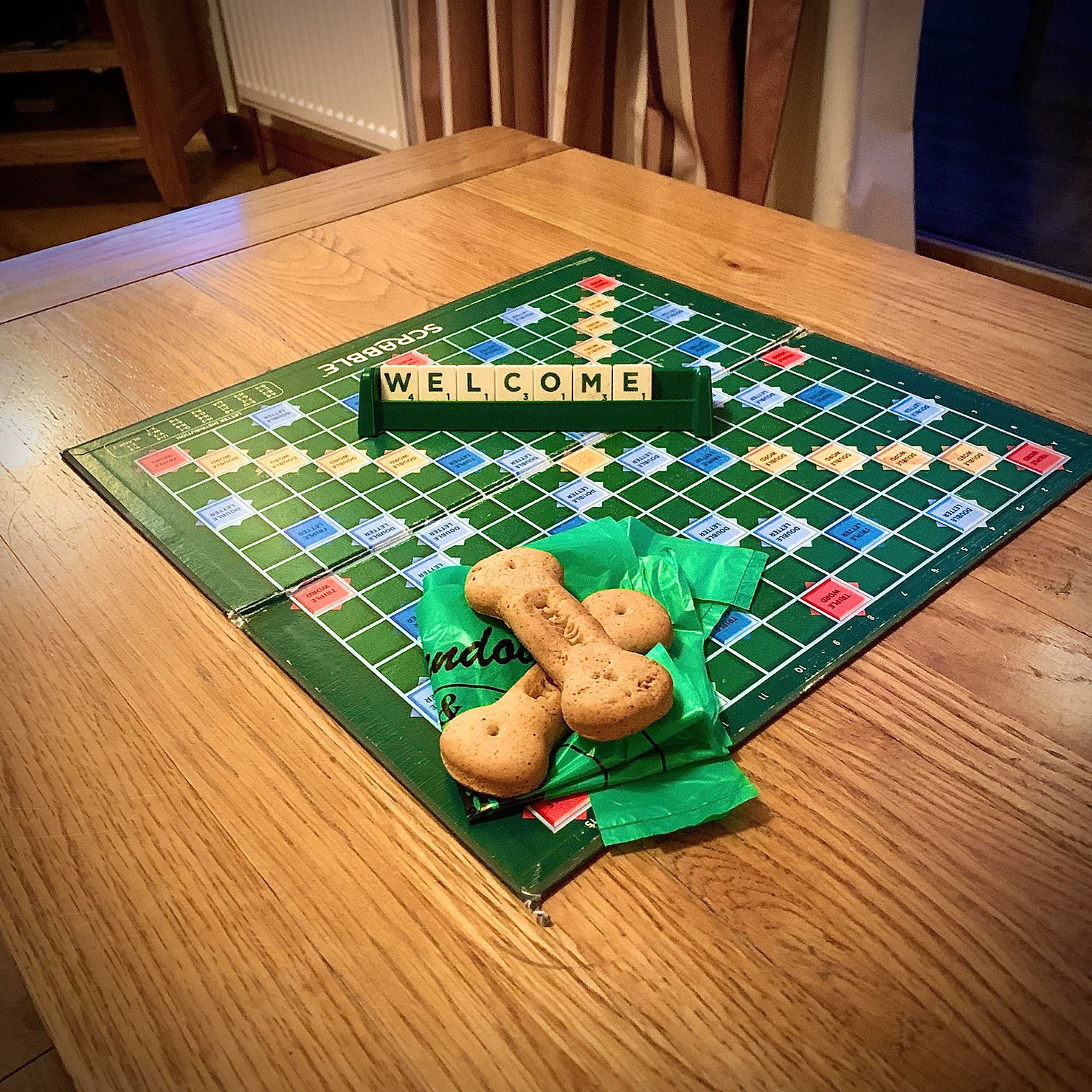 Scrabble board spelling out the words "WELCOME", alongside two dog biscuits from staff