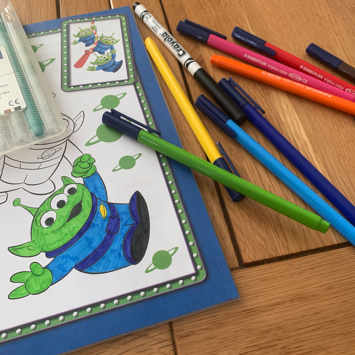 Colouring pens scattered across Ross's kitchen table, with a half coloured green toy story alien