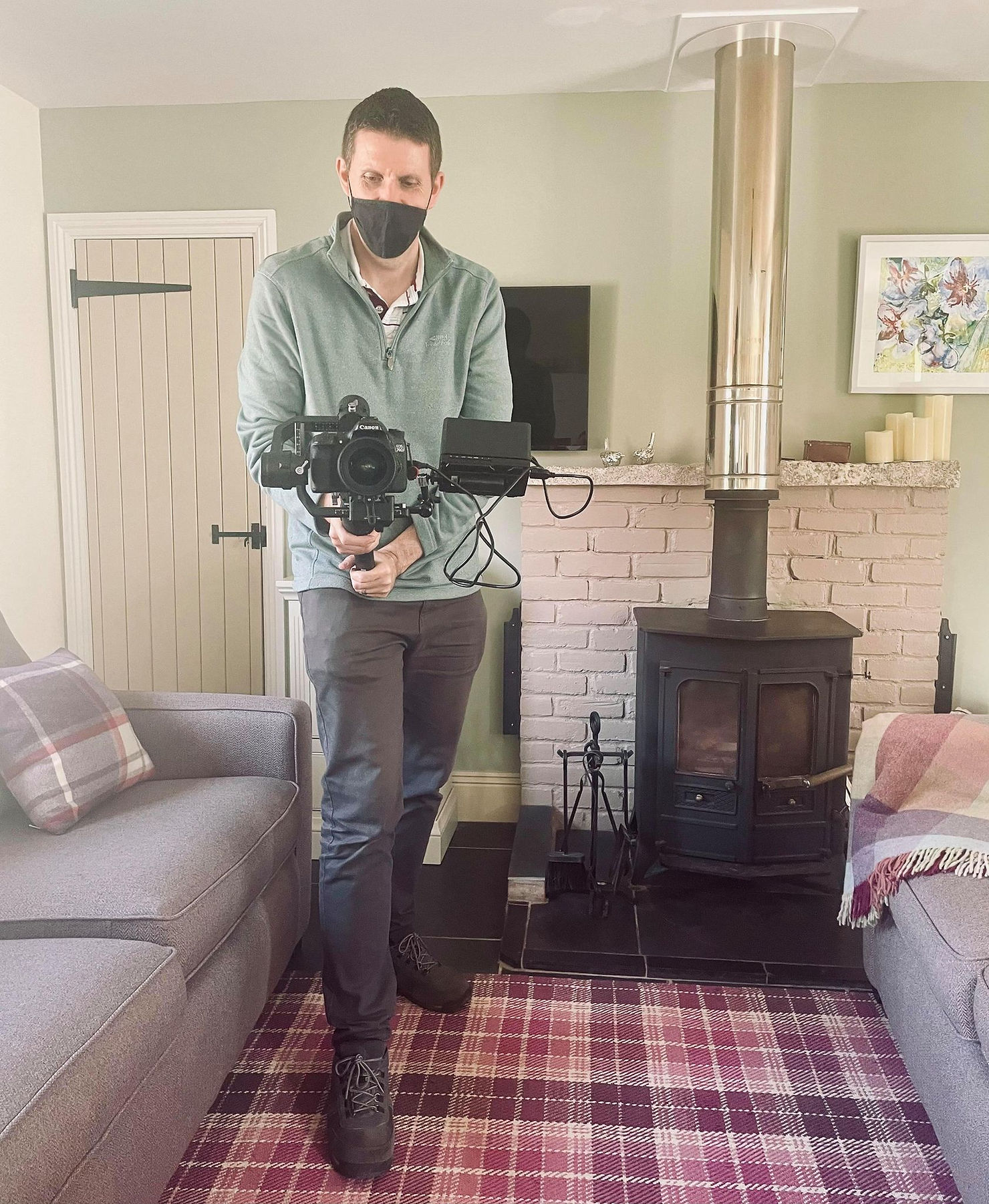 Behind the scenes shot of Neil holding a big recording camera filming Ross