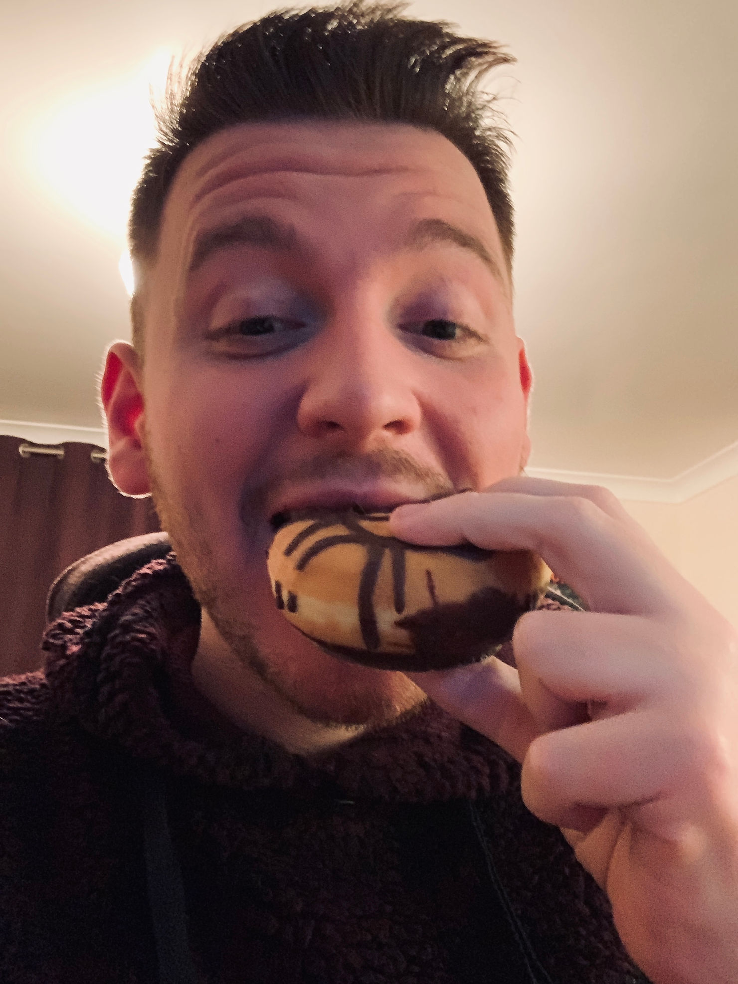 Selfie of Ross whilst taking a bite out of a chocolate doughnut