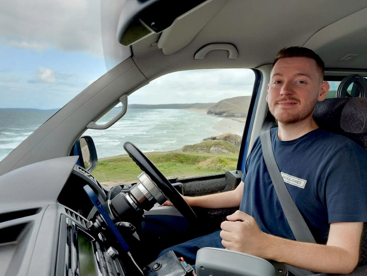 Ross sat in his wheelchair in the drivers position. Sea view through the window in the background