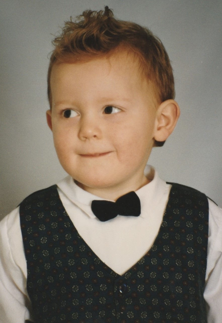 Baby Ross wearing a bow tie and waistcoat, looking cheekily away from the camera