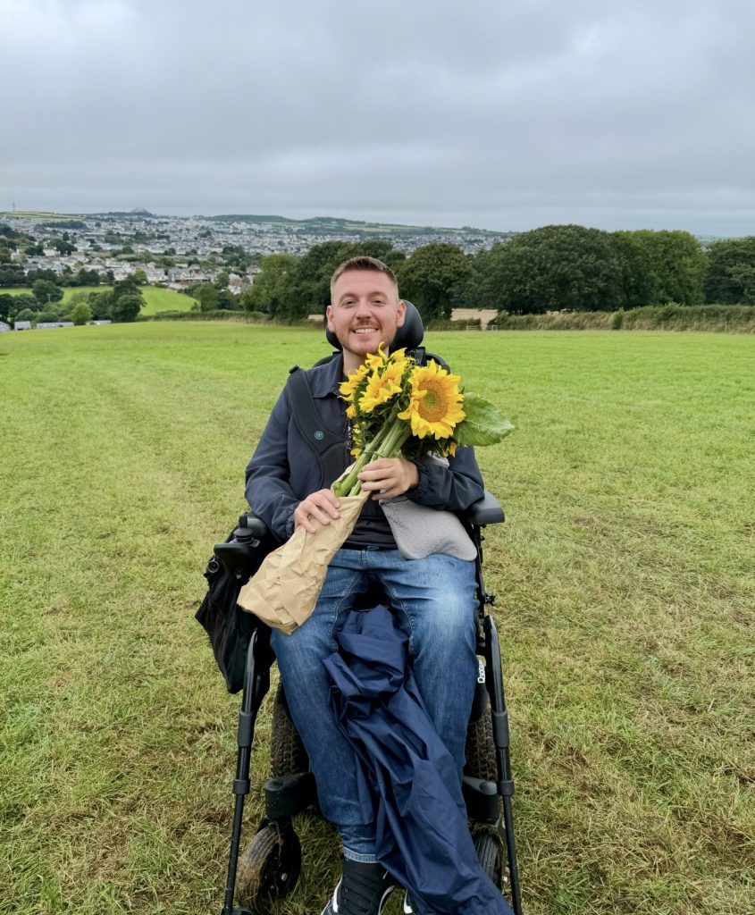 Ross holding a bunch of sunflowers in the middle of a field.