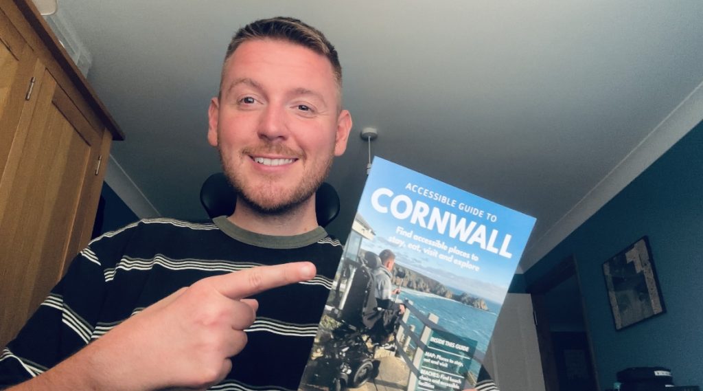 Ross holding the accessible huide to Cornwall booklet