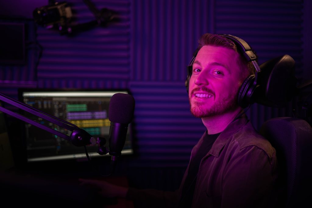 Ross inside the radio studio wearing headphones at the desk.